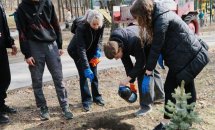 Хлопець наливає рідину у ямку, біля нього стоять дві жінки.
