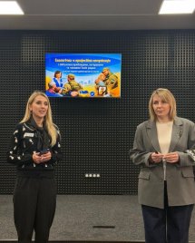 Дві жінки на фоні звукоізолюючої стіни та телевізору.