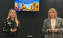 Дві жінки на фоні звукоізолюючої стіни та телевізору.