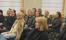 Група жінок сидить у залі.