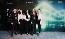 Чотири жінки та чоловік позують на фоні банера.