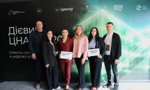 Два чоловіка та чотири жінки фоторграфуються на фоні банера.