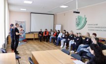 Чоловік в чорному одязі стоїть перед групою осіб
