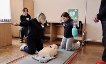 Дві жінки стоять на колінах біля манекена тримаючи руки підняті у сторони