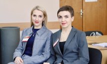 Дві жінки з бейджами посміхаються