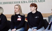 Дві жінки в темному одязі сидять у приміщенні.