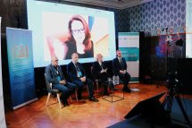Троє чоловіків та жінка сидять перед екраном.