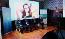 Троє чоловіків та жінка сидять перед екраном.