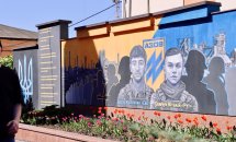 Мурал із зображенням військових і символікою Азов на стіні, перед якою висаджені тюльпани.