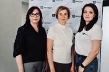 Три жінки позують на фоні банера.
