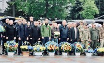 Шість жінок у діловому одязі з маками позують для спільного фото.
