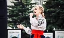 Жінка в українському костюмі тримає мікрофон.
