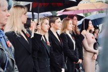 Група жінок у чорному одязі стоять надворі.