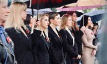 Група жінок у чорному одязі стоять надворі.