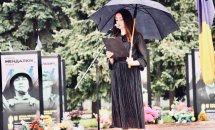 Жінка у чорному одязі тримає чорну парасолю.