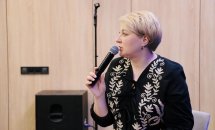 Жінка з короткою зачіскою у вишиванці тримає мікрофон.