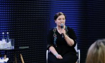 Жінка у чорному одязі тримає мікрофон у руках.