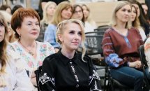 Жінки у вишитих сорочках сидять у залі.