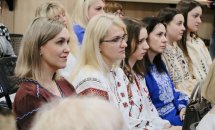 Група жінок у вишиванках сидять у залі.