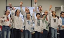 Діти у вишиванках підняли одну руку вгору.