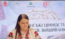 Жінка у вишиванці тримає чорну папку.