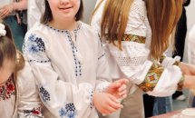 Дівчинка у вишиванці стоїть біля столу.