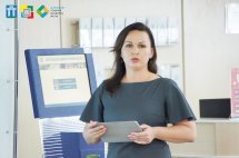Жінка з довгим волоссям виступає перед аудиторією.