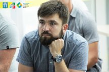 Молодий чоловік із бородою уважно слухає.