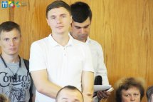 Чоловіки стоять у залі та уважно слухають.