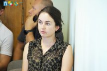 Жінка в чорній блузі уважно слухає.