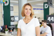 Жінка з коротким волоссям та в білому одязі перебуває у приміщенні.
