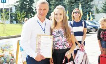 Чоловік та дівчина позують для фото з грамотою у руках.