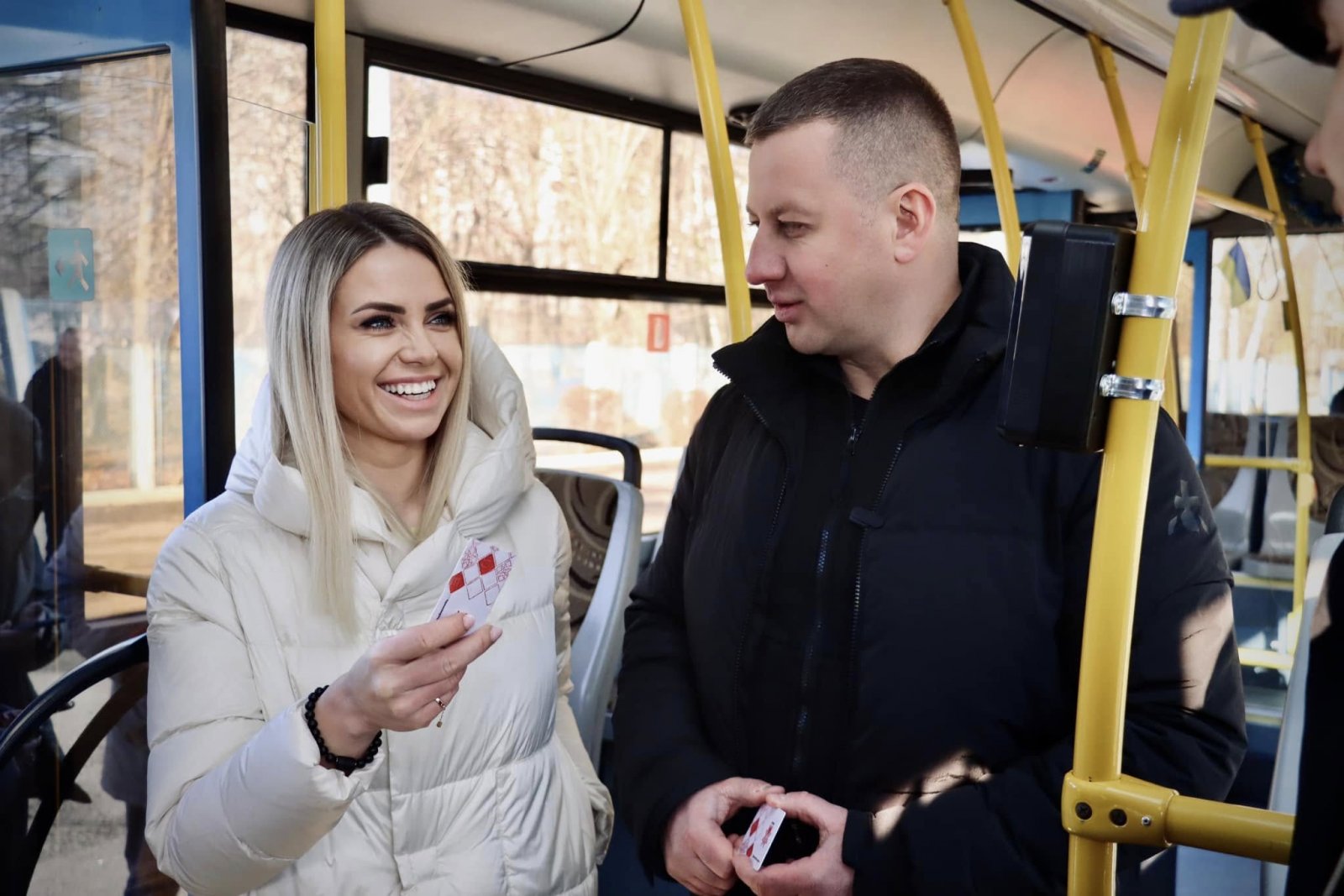 У тролейбусі жінка тримає картку для безконтактної оплати проїзду. Поруч стоїть чоловік.