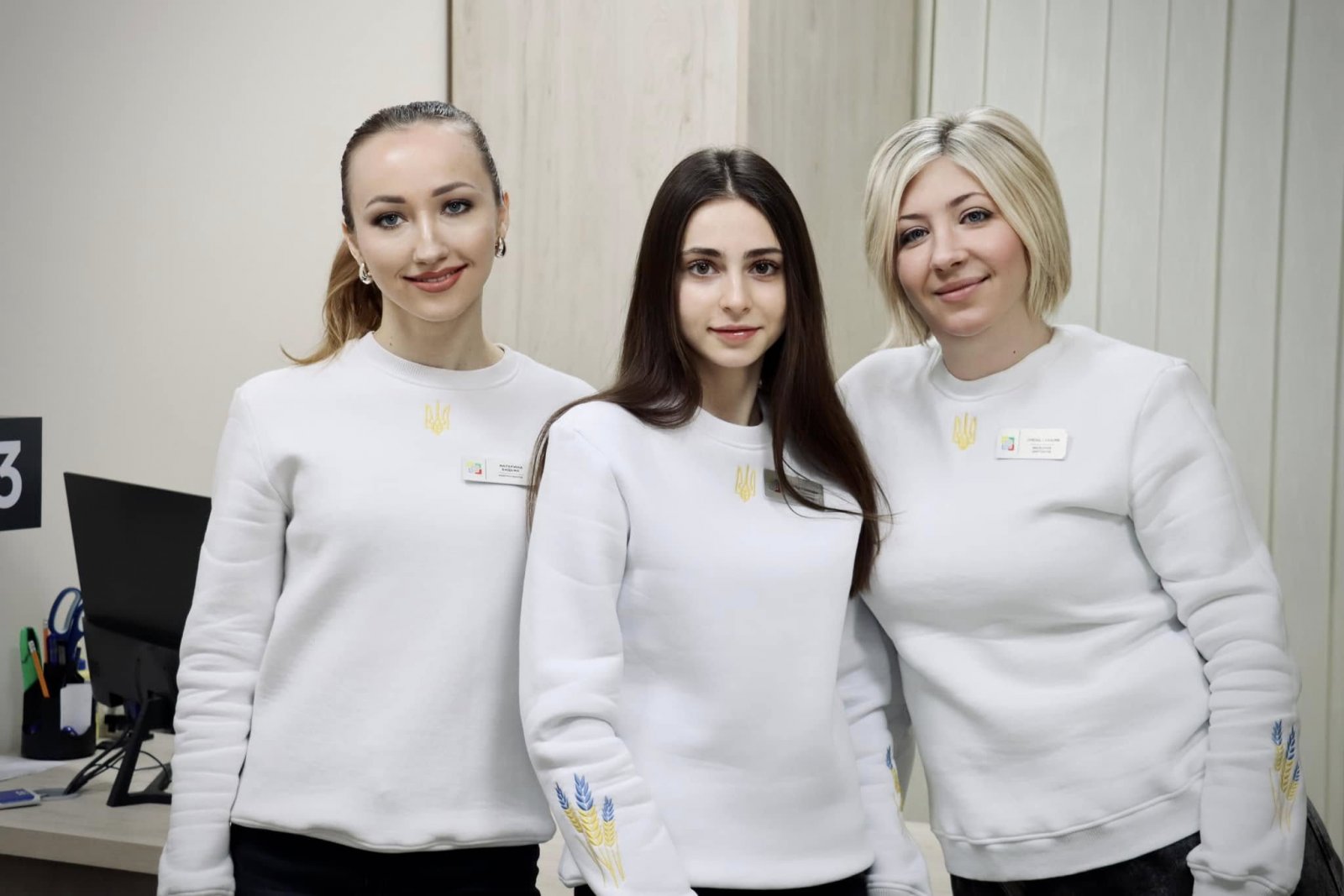 Працівники ЦНАПу одягнені у білі кофти з вишитим золотим гербом України.