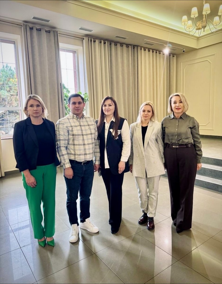 Чоловік та чотири жінки стоять у приміщенні.