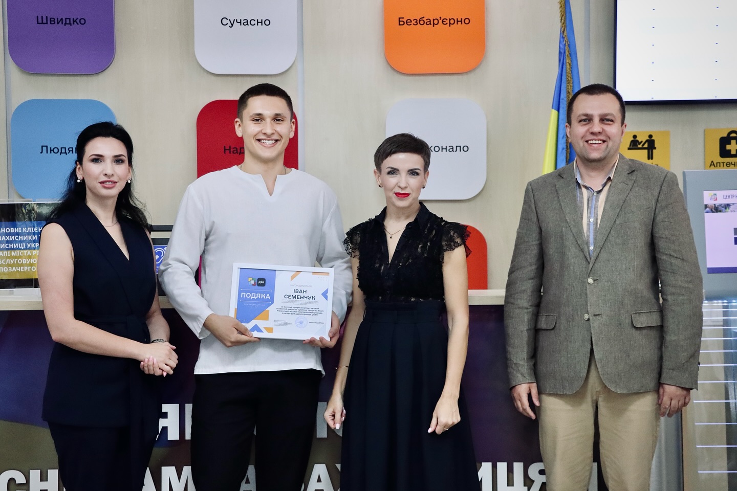 Дві жінки та два чоловіка позують для фото, один із чоловіків тримає подяку.