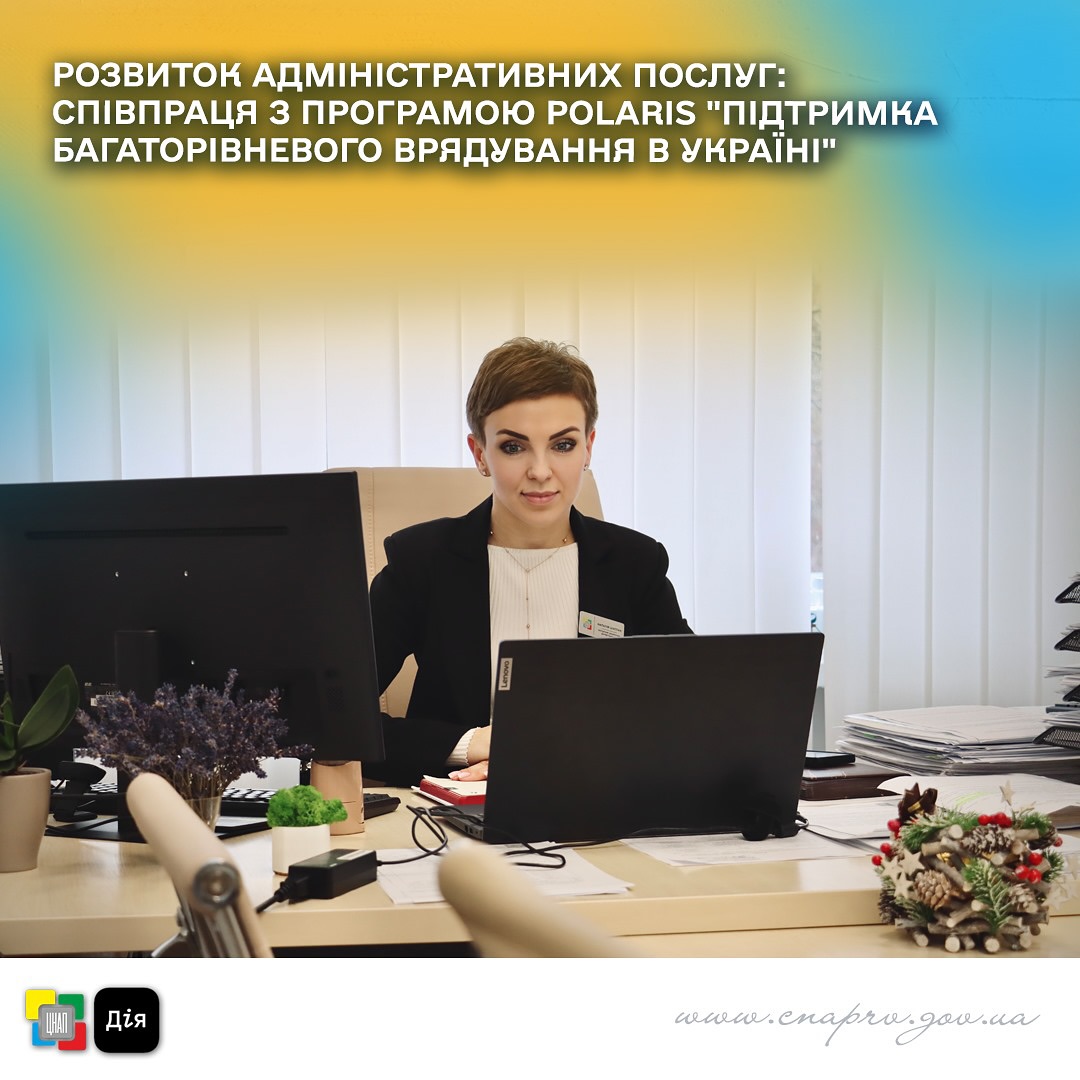 Жінка, у діловому костюмі, сидить в робочому кабінеті та працює за ноутбуком.