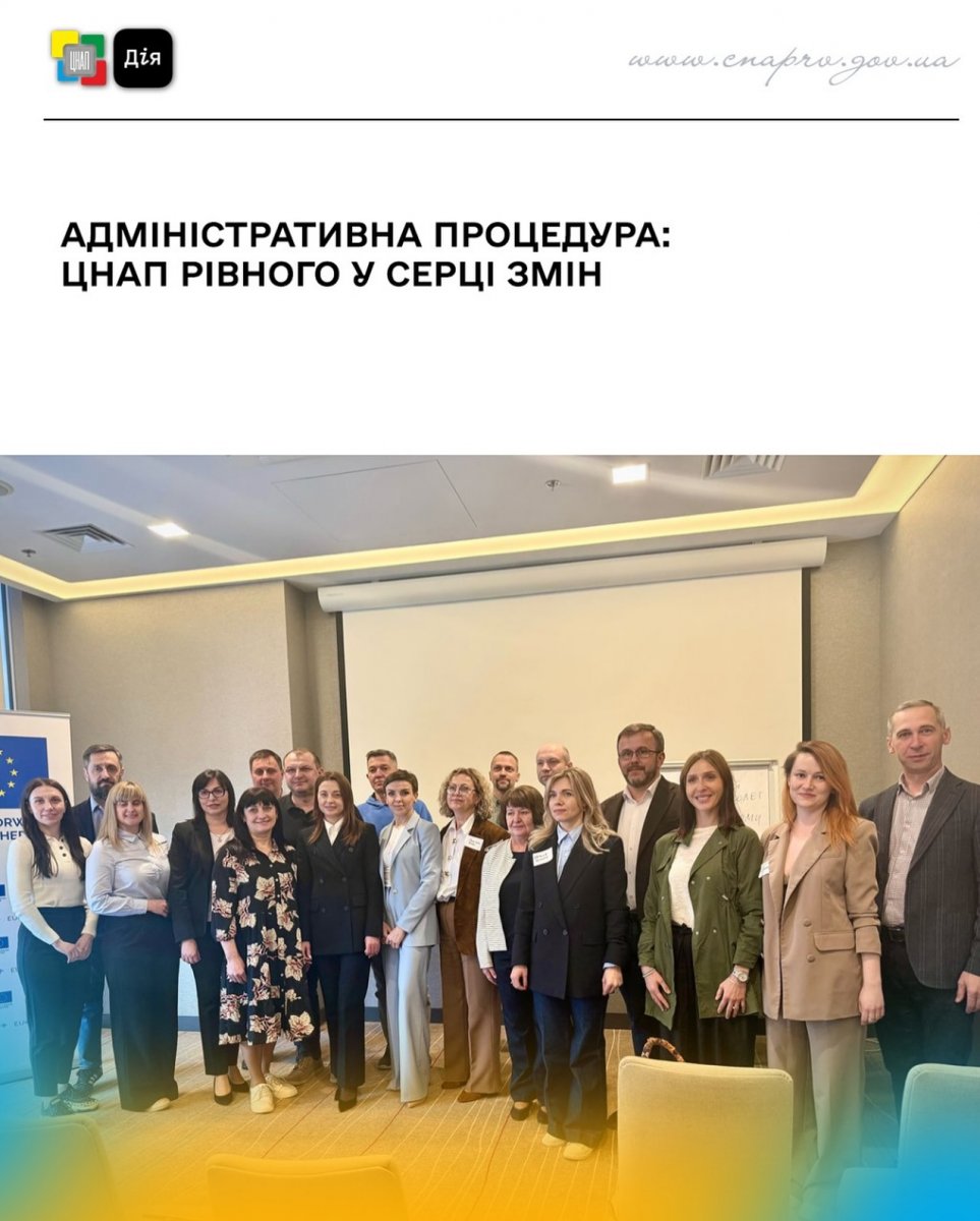 Групове фото учасники заходу біля екрану в конференц-залі.