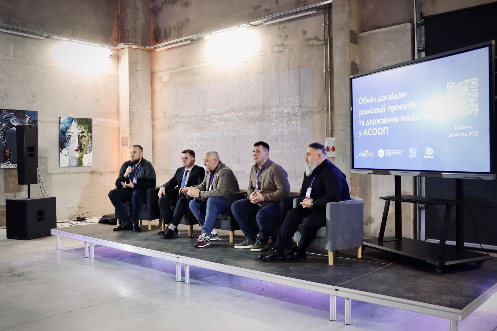 П'ять чоловіків сидять перед екраном.