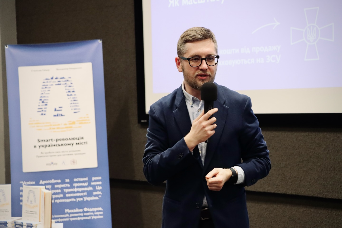 Чоловік в окулярах тримає мікрофон у руках.