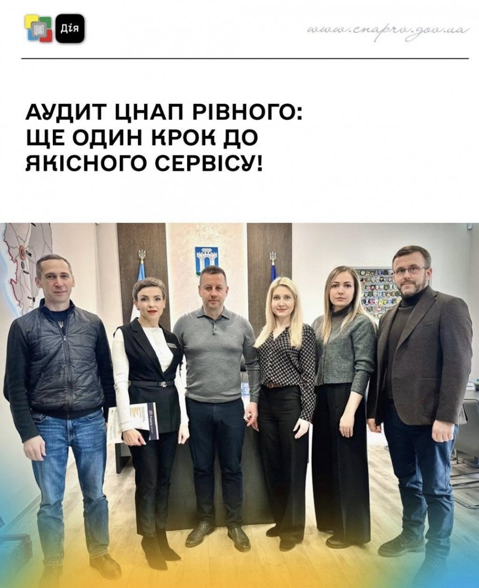 Троє чоловіків і троє жінок стоять перед гербом міста, ймовірно, в адміністративній будівлі. 
