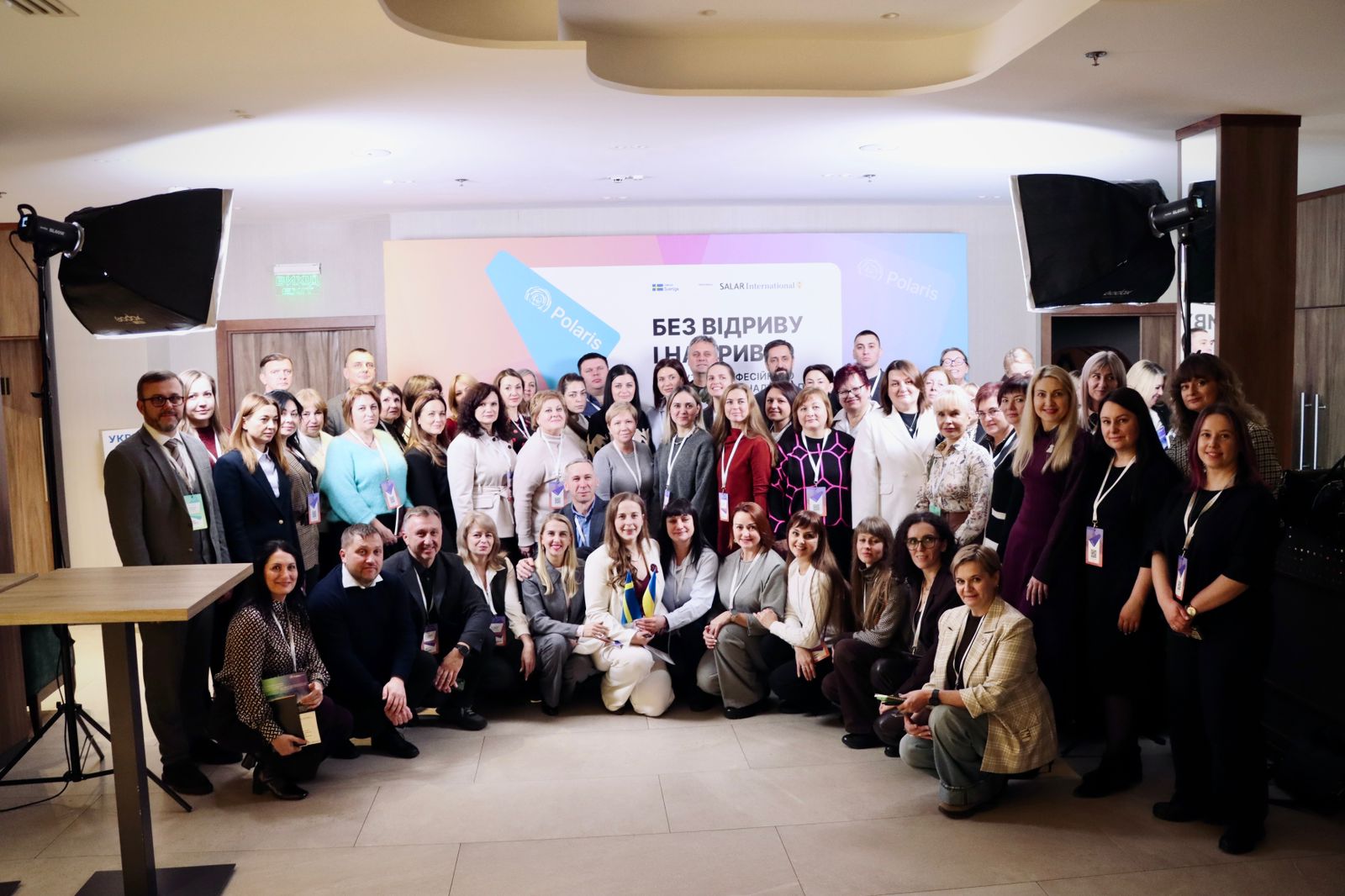 Багато людей позує для спільного фото на фоні банера.