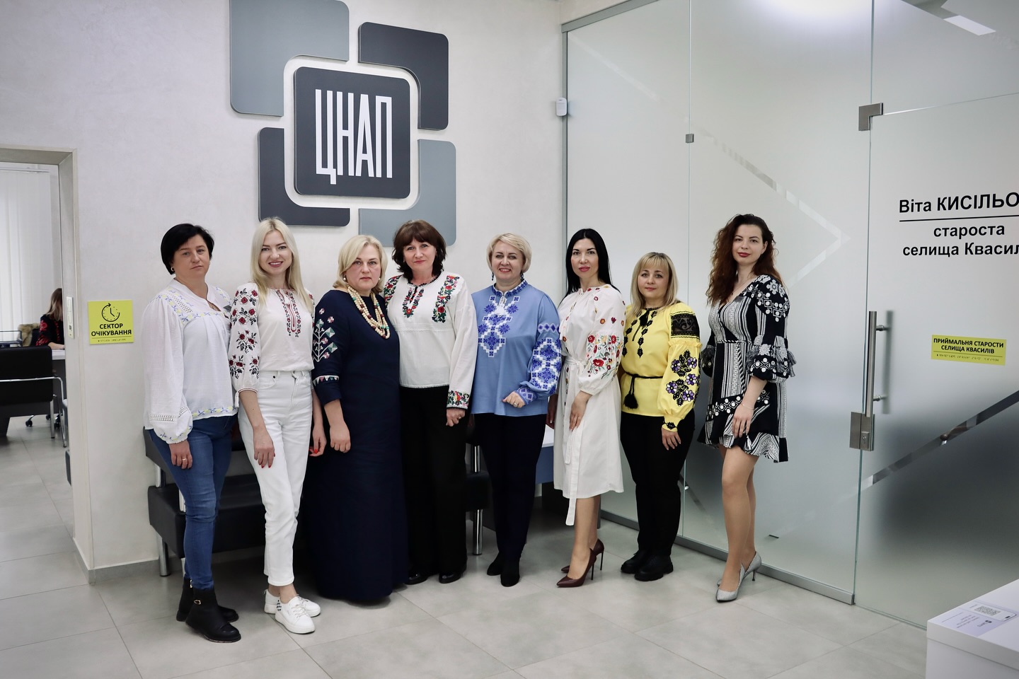 Жінки у вишитому одязі позують для фото у приміщенні.