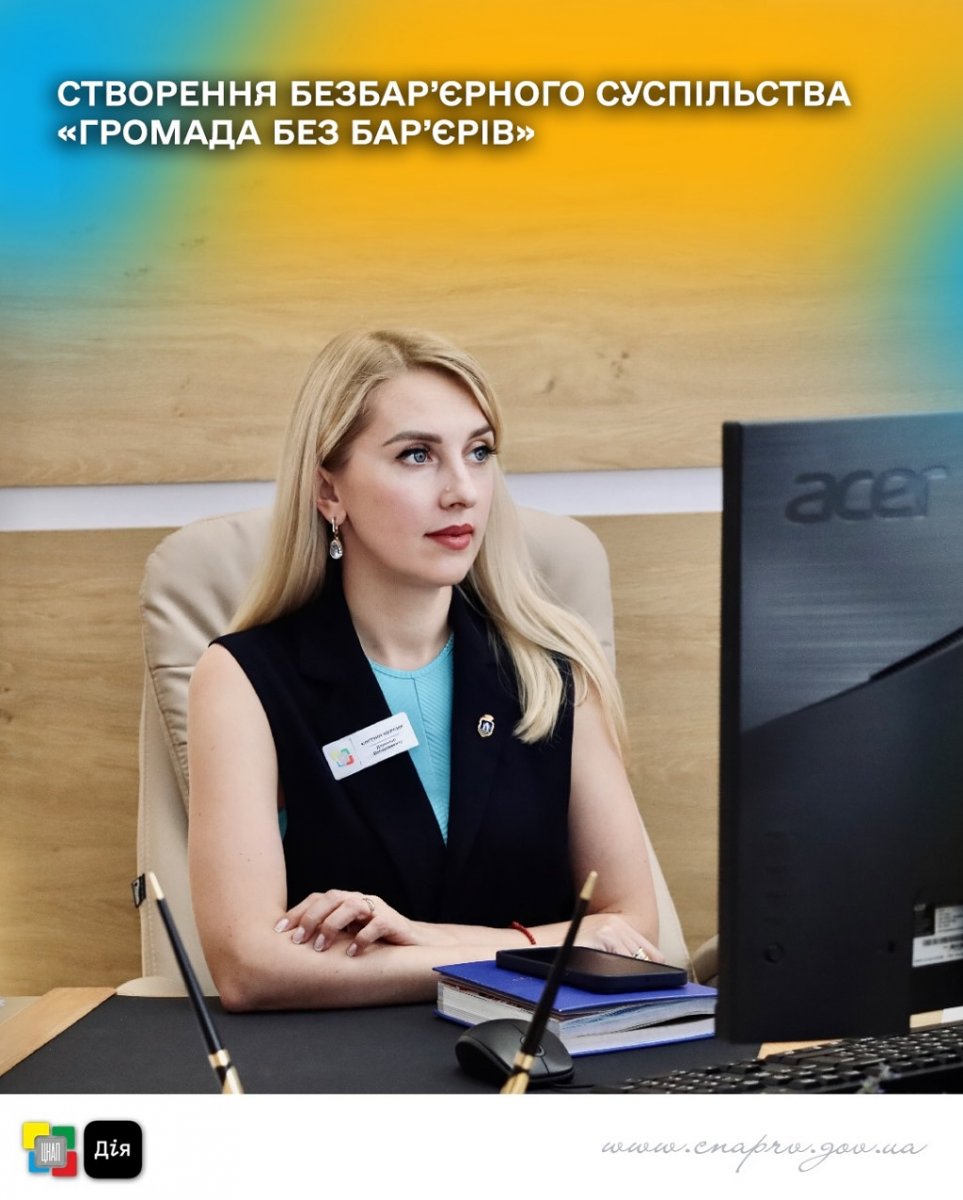 Жінка зі світлим волоссям у діловому одязі сидить за комп'ютером