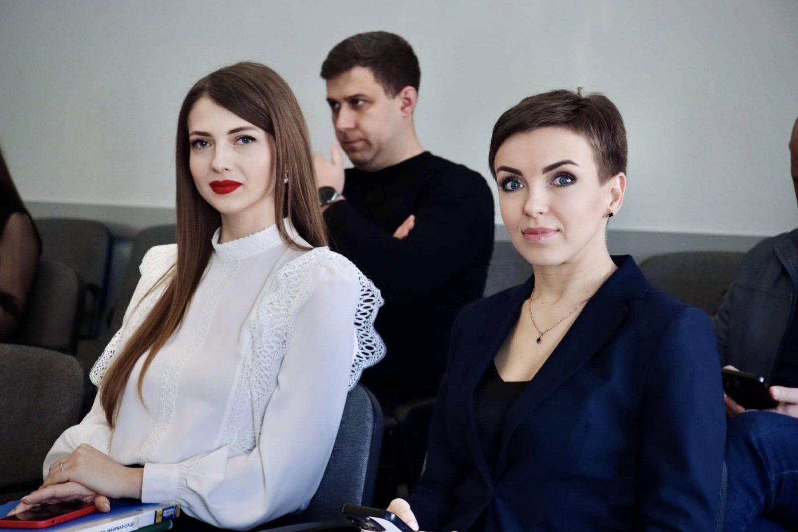 Дві жінки в костюмах сидять у залі