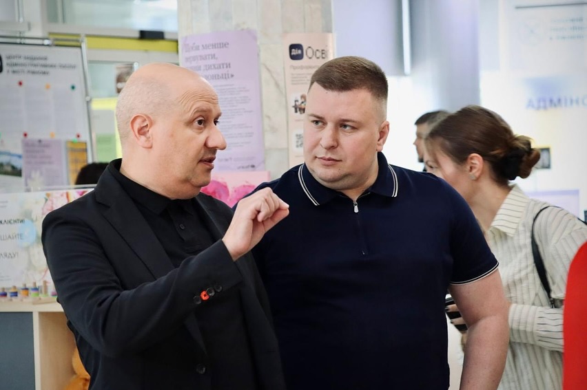 Двоє чоловіків перебувають у приміщенні, один щось розповідає.