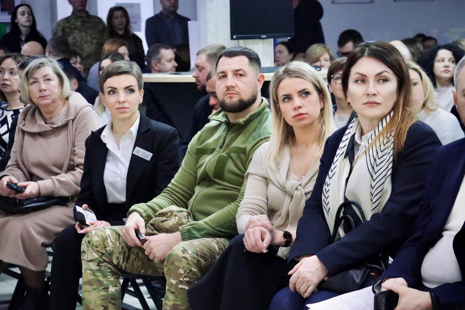 Люди сидять в приміщенні ЦНАПу і слухають доповідь.