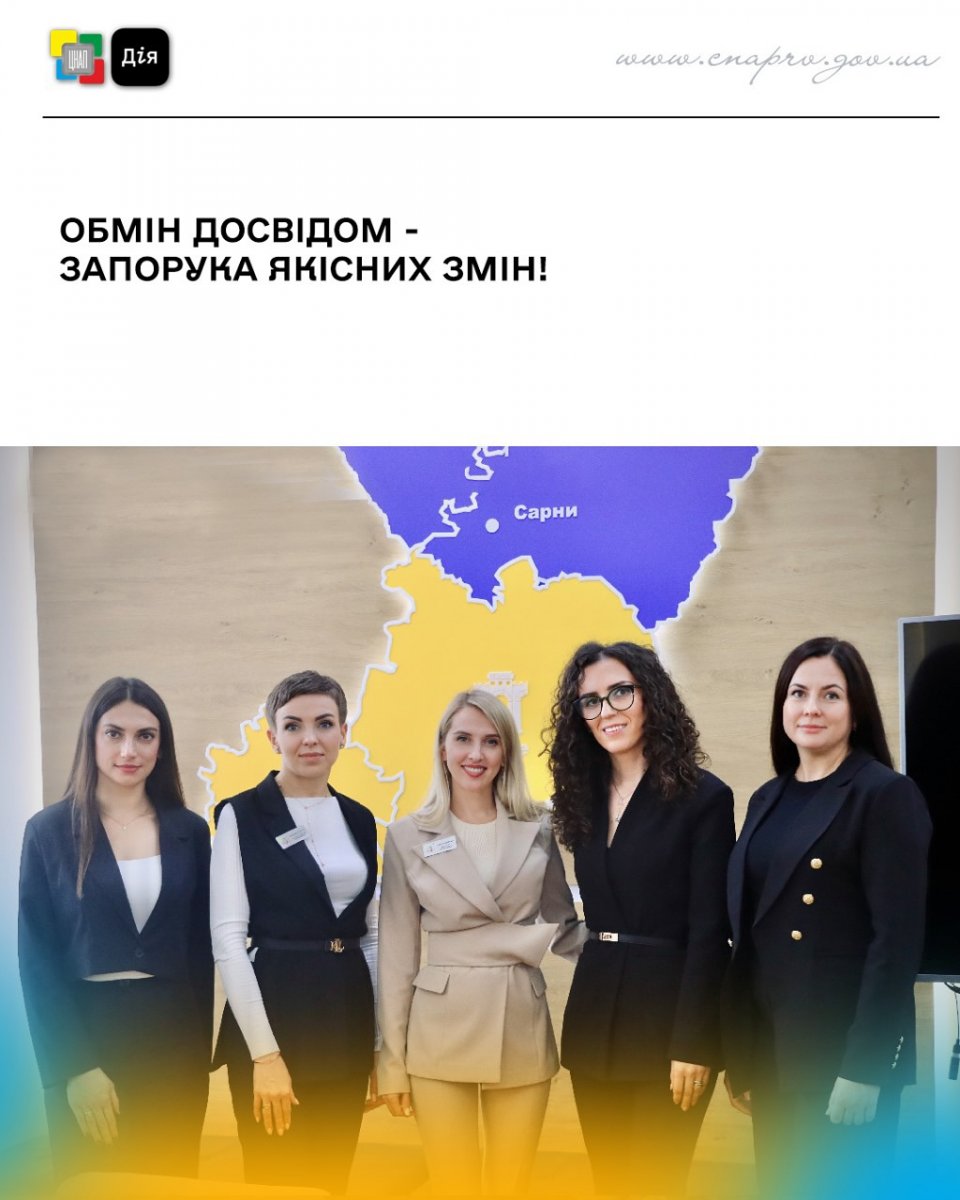 П'ять жінок у діловому одязі позують у приміщенні.