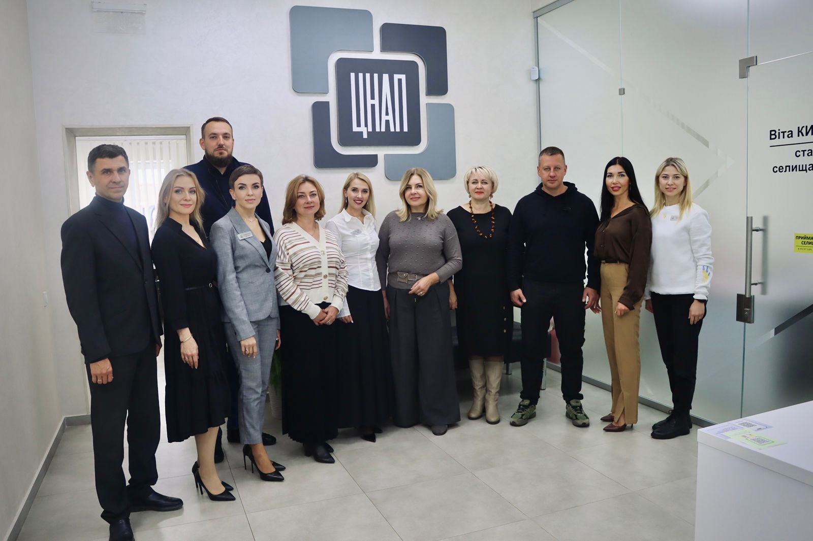 Групове фото у приміщенні, на задньому фоні є вивіска ЦНАП