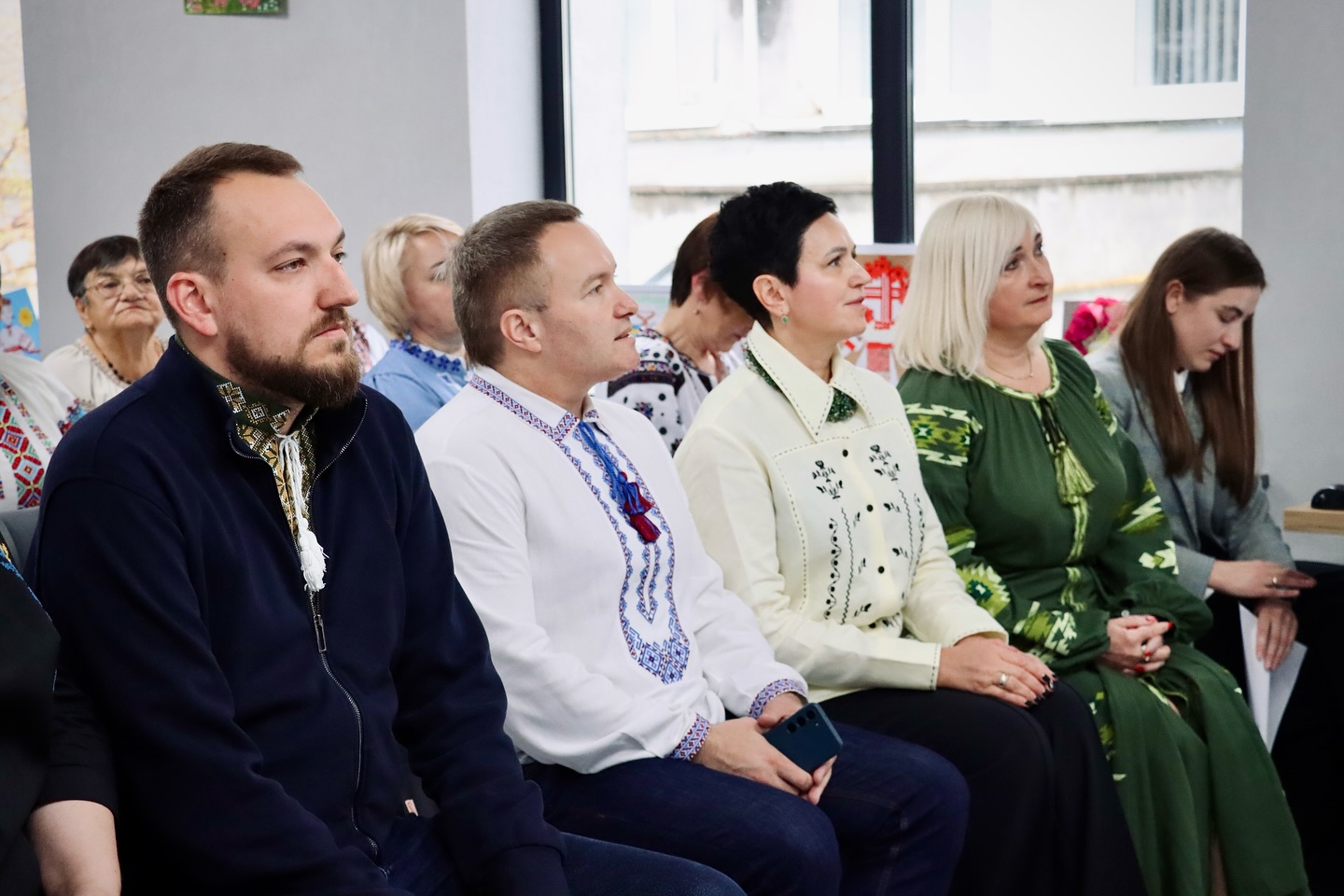 Люди у вишиванках сидять у приміщенні.